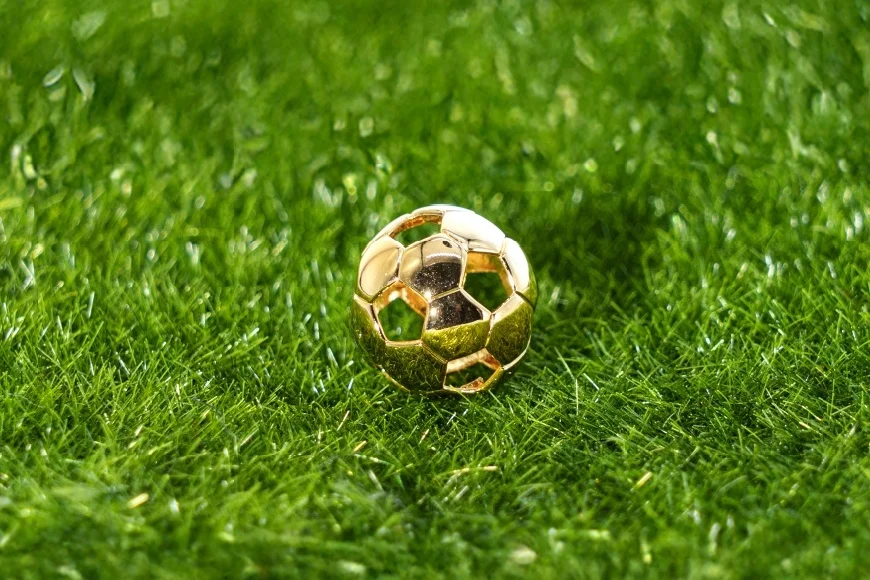 芝の上に置かれたゴールドカラーのサッカーボールジュエリー